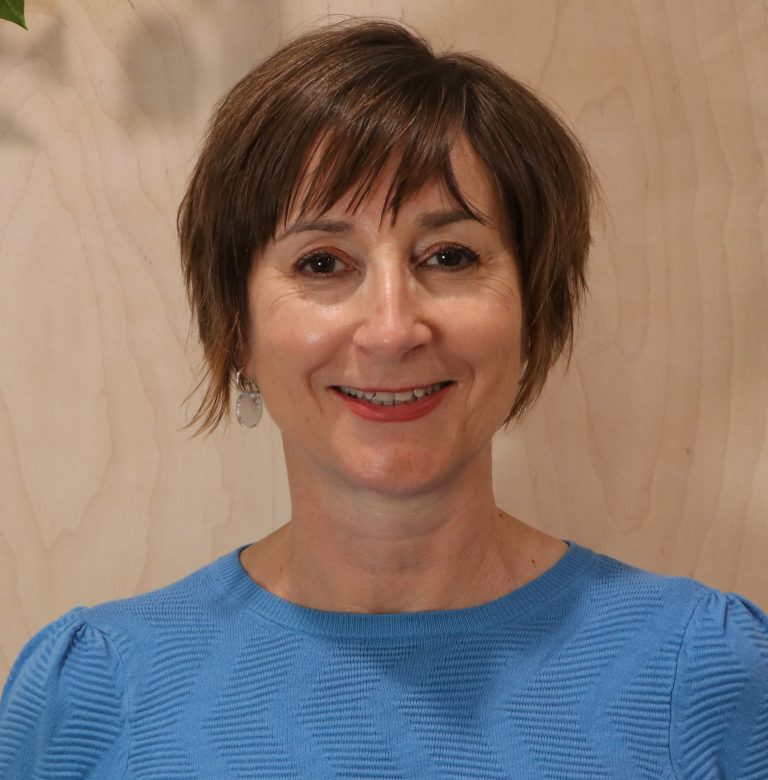 Portrait of a smiling woman in a blue shirt.