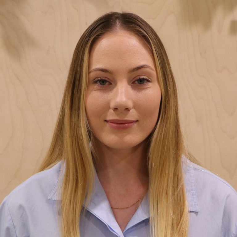 Young woman with long blond hair in a light blue shirt.