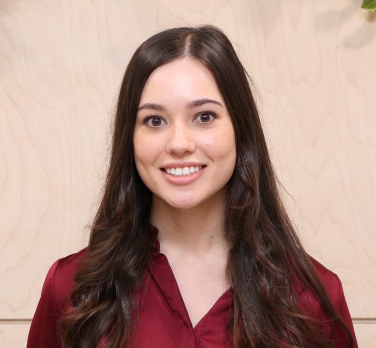 A smiling young woman with long hair, wearing a red blouse.
