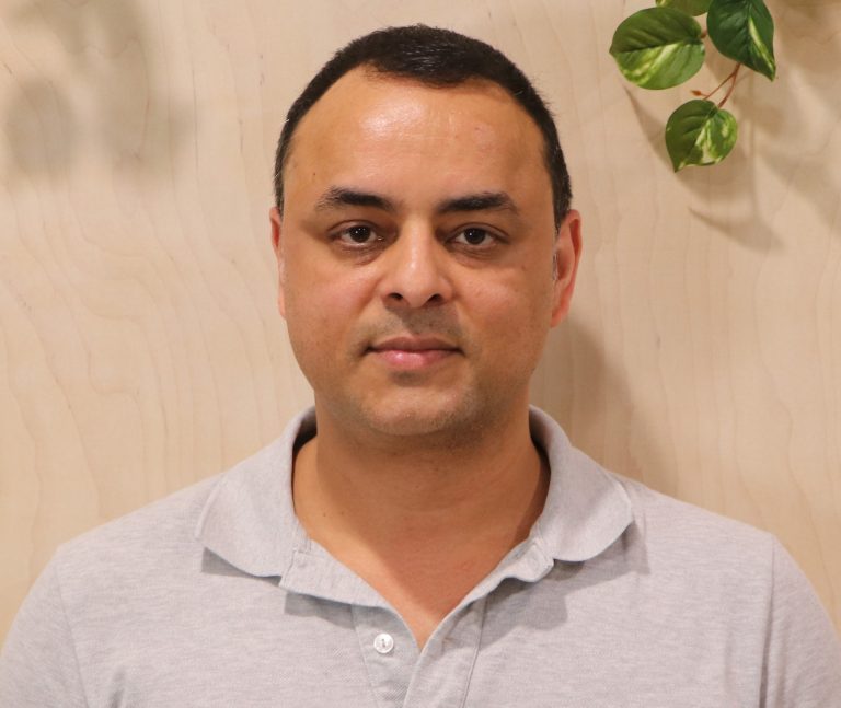 Portrait of a man in polo shirt with plants, showcasing a natural environment.